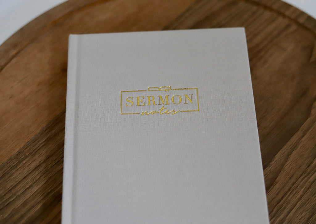 White notebook with 'Sermon Notes' embossed in gold on a wooden surface